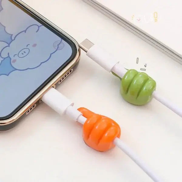 Phone with a USB cable shaped like a green and orange hand holding a carrot, on a light surface.