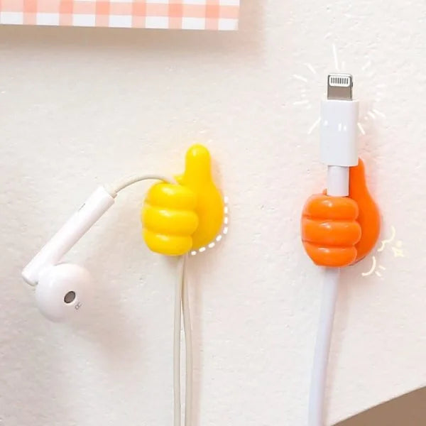 Two thumb-shaped cable holders on a light wall, one yellow holding white earbud wires and one orange holding a white lightning cable, with decorative sparkles near the connectors.