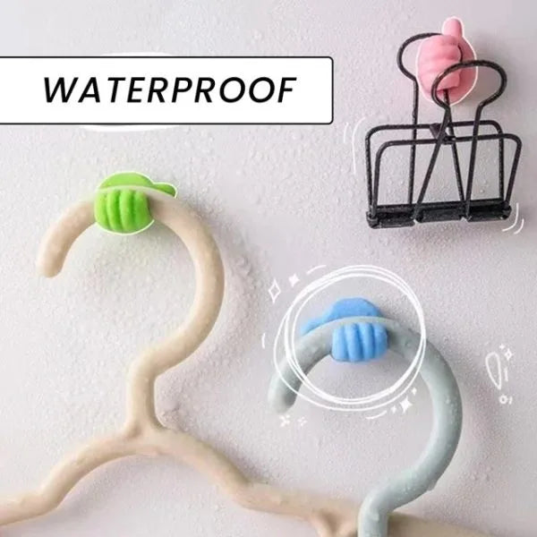 Three plastic clothes hangers in beige, light blue, and black, each fitted with a small colored grip at the hook. A white label at the top reads “WATERPROOF,” and the background is a light textured white surface.