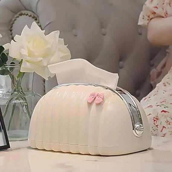 Small white appliance with a pink bow on a surface, with a blurred background