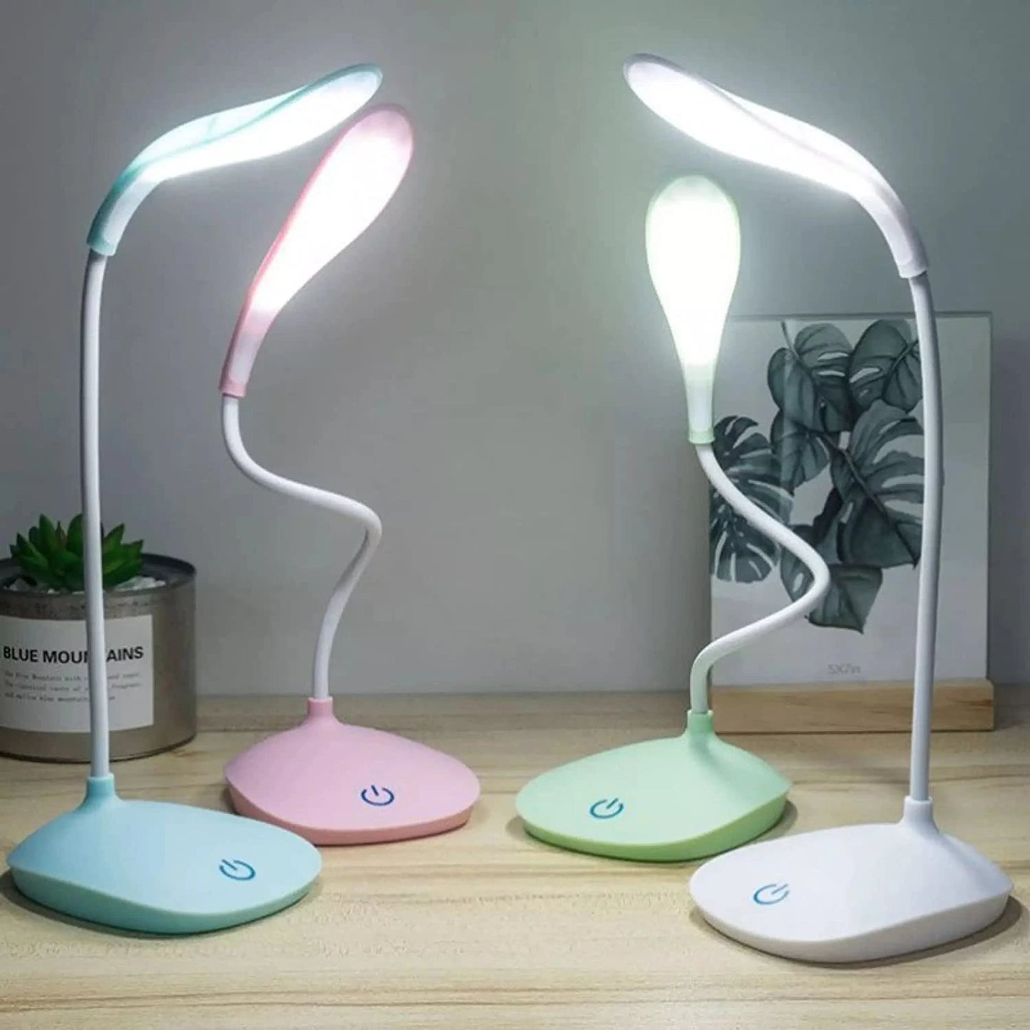 Four colorful desk lamps on a wooden surface with a neutral background