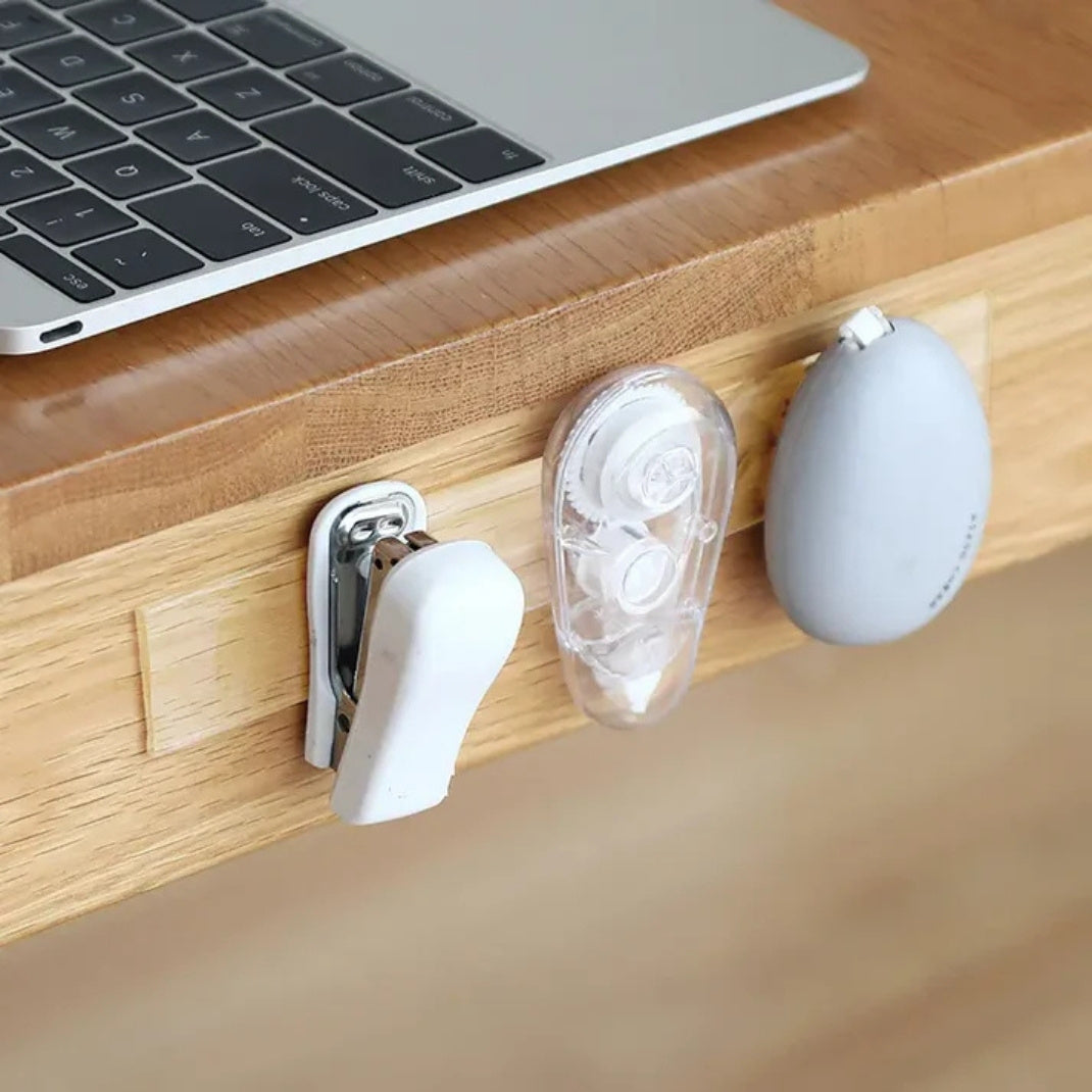 Three small white devices on a wooden surface next to a laptop.