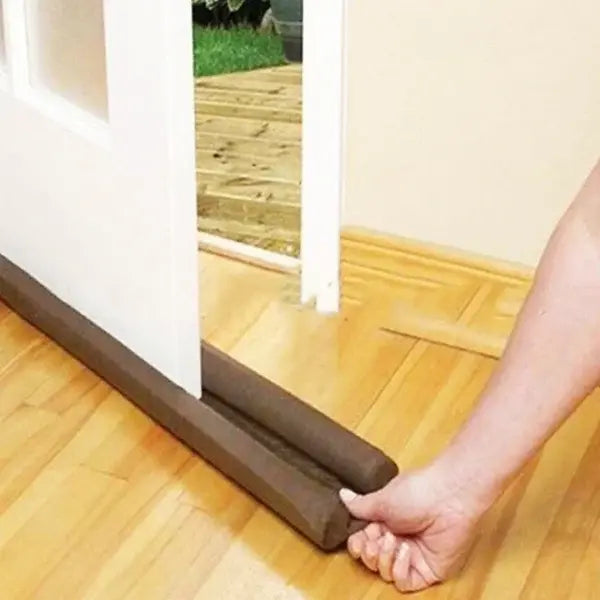 Brown door draft excluder being used to seal a gap under a door.