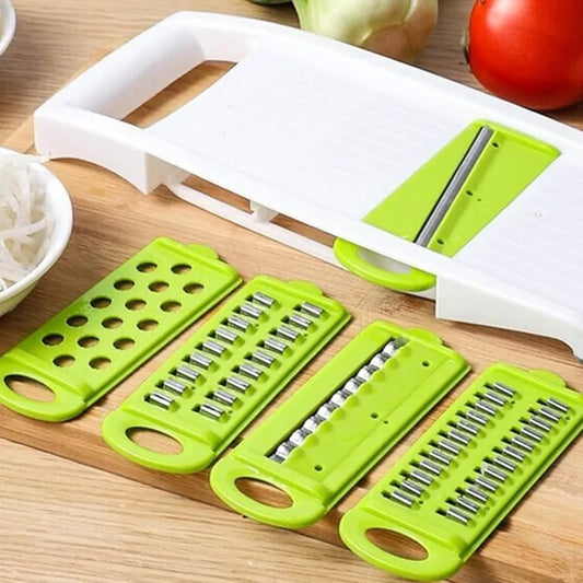 Green and white adjustable vegetable slicer on a wooden cutting board with vegetables in the background.